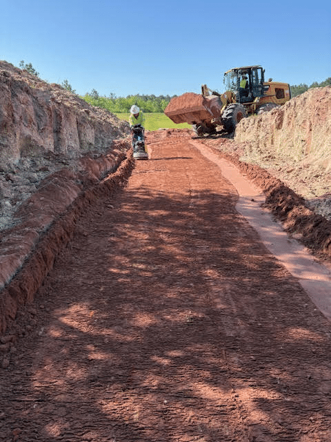 A man cleaning up the ground and an excavator loaded with soil A man cleaning up the ground and an excavator loaded with soil